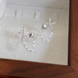 Détail des boucles d'oreilles étoile de mer et coquillage avec zircons et perles