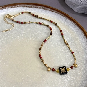 Detail of vintage beaded necklace with green leaf charms and gold lobster clasp
