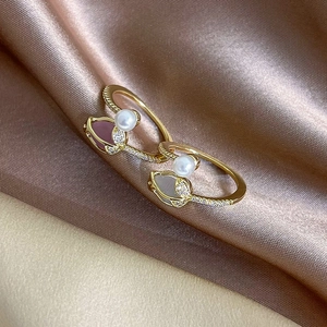Elegant gold tulip rings with pink and grey pearls on soft satin background