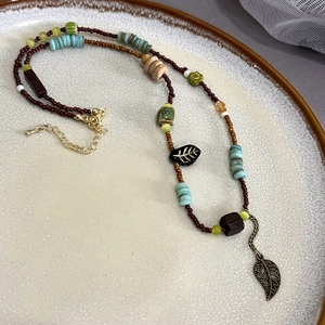 Detailed shot of ethnic beaded necklace featuring green leaves and vintage bohemian charms