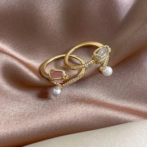 Elegant gold tulip rings with pink opal and pearls on champagne silk fabric background