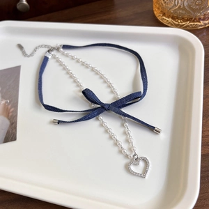 Detailed shot of double-layer denim bow choker with white faux pearl and heart pendant