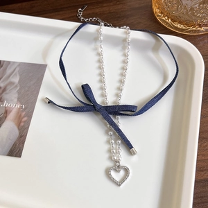 Double-layered denim choker with pearl bow and heart rhinestone pendant on a tray