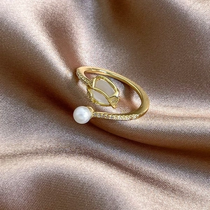 Close-up of gold tulip ring with white gemstone, pearl and pavé crystals on silk fabric