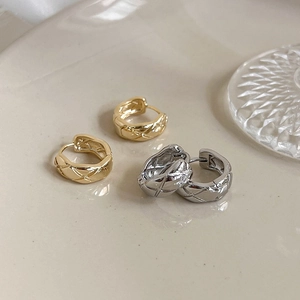 Checkered pattern metal hoop earrings in gold and silver finish on a stylish tray