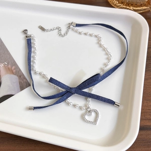 Detailed close-up of double-layer choker with denim bow and crystal heart pendant