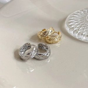 Close-up of quilted pattern metal hoop earrings in gold and silver finish