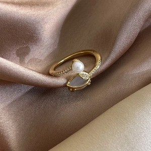 Detail of gold-plated tulip ring with white pearl, cat-eye stone, and micro-set crystals