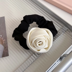 Gros plan d'un chouchou en satin fait main avec une fleur de rose aux pétales superposés