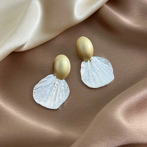 Elegant gold oval studs with silver shell-shaped metallic fan earrings on satin fabric