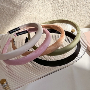 Detail view of five jacquard satin headbands in neutral tones with handmade fabric labels