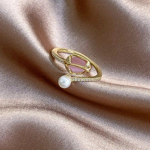 Close-up of tulip ring with pink gemstone and pearl on champagne silk fabric