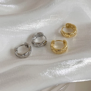 Macro shot of gold and silver hoop earrings featuring a quilted pattern on white silk