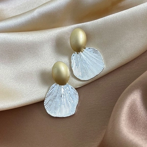 Elegant gold and silver two-tone shell textured stud earrings on luxury silk fabric