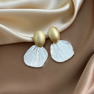 Detailed macro of vintage metal shell earrings on elegant champagne silk fabric