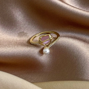 Detailed shot of tulip pearl open ring with pink stone and zircon on silk fabric
