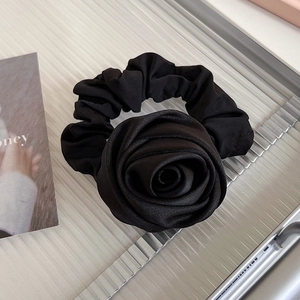 Vue détaillée du chouchou en satin noir avec rose 3D et texture soyeuse multicouche