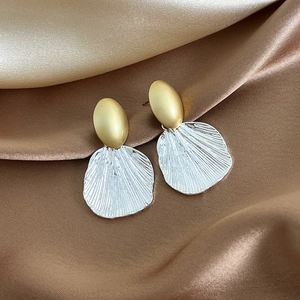Macro view showing the contrast of golden oval studs and silver shell-textured fan drops