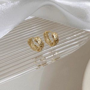 Detailed view of golden hoop earrings with quilted pattern on a glass plate