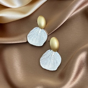 Macro shot of bicolor shell earrings in matte gold and silver with ribbed texture