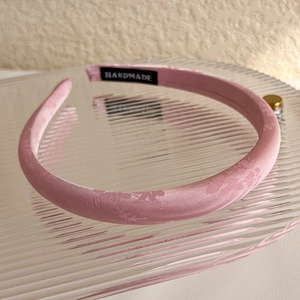 Detailed macro view of pink jacquard satin headband with elegant floral texture