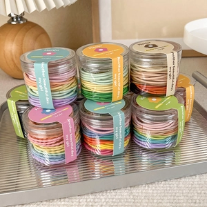 Close-up of high-elasticity candy colored hair ties in a transparent storage jar