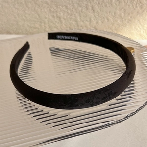 Close-up of black jacquard satin headband featuring handmade label and floral texture