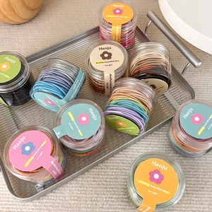 Close-up of colorful elastic hair bands packed in a transparent round plastic jar