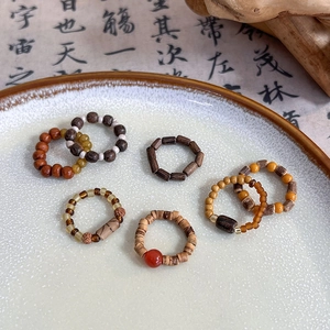 Handmade Chinese style ring with wooden beads and red agate on a white ceramic plate