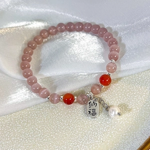 Makroaufnahme von Katzenaugen-Armband mit Silberanhänger und Perle auf Seidenstoff