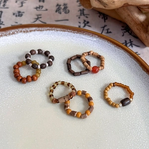 Handmade Chinese style beaded rings with natural wood, agate, and jade beads on a ceramic plate