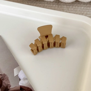 Matte aprikosenfarbene Mini-Haarklammer auf einem weißen Tablett im natürlichen Licht