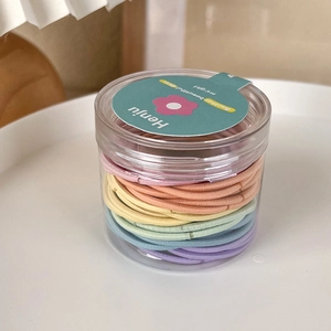 Colorful seamless elastic hair ties set in a clear jar with a floral lid on a tray