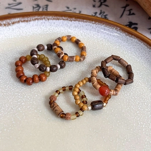 Close-up of handmade retro wood beads and stone rings in a ceramic plate with calligraphy