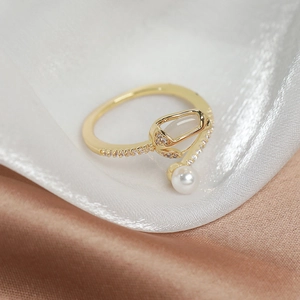 Detail of tulip ring with white pearl and inlaid stones on champagne silk background