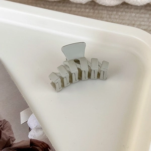 Detailaufnahme einer matten cremefarbenen Mini-Haarklammer auf einem weißen Tablett