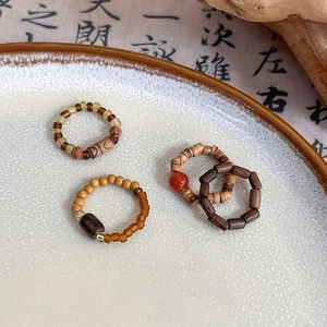 Close-up of handmade retro Chinese style rings with stone and wood beads in a ceramic tray