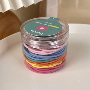 Close-up of assorted candy colored high elastic hair ties in a transparent plastic jar
