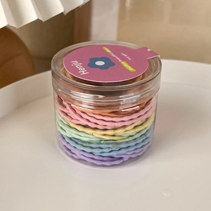Macro shot of colorful wavy hair ties in a clear plastic jar for dopamine girls style