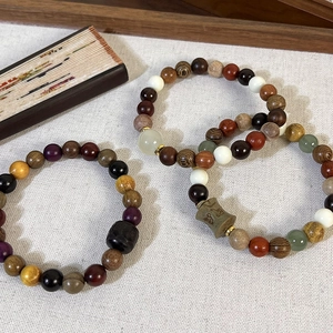 Détail de perles de bois de santal avec tube gravé et agate sur lin texturé