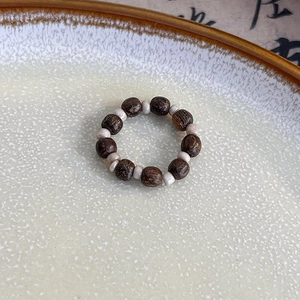 Macro shot of handmade beaded ring with dark wood beads and beige stone accents