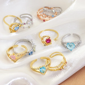 Assorted gold and silver rings with heart and crown designs on white silk background