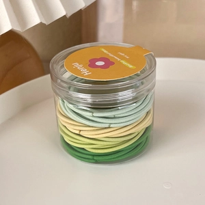 Colorful elastic hair ties in a clear cylinder container with a yellow lid and label