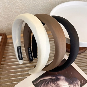 Three padded satin headbands in beige, brown, and black with hand made label detail