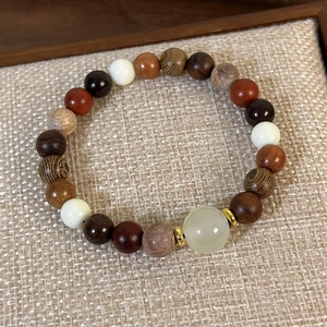Gros plan d'un bracelet en perles de bois de santal avec jade vert et intercalaires dorés