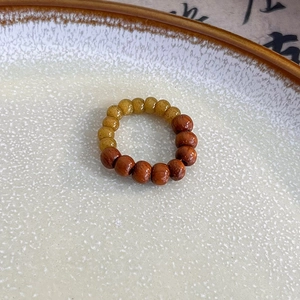 Detail of handmade Chinese style ring with wooden beads and amber-like resin spheres