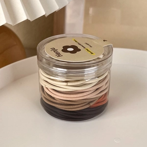 Close-up of assorted earth-tone elastic hair ties in a transparent storage jar