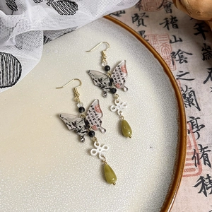 Dettaglio di orecchini a farfalla vintage con pittura a inchiostro cinese e nappe eleganti