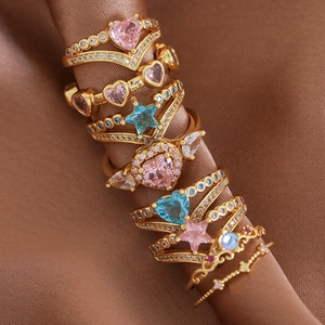 Set of gold-plated rings with heart and star zircon stones on brown silk background