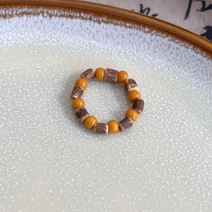 Macro shot of handmade orange and dark brown beaded ring with natural stone and wood texture
